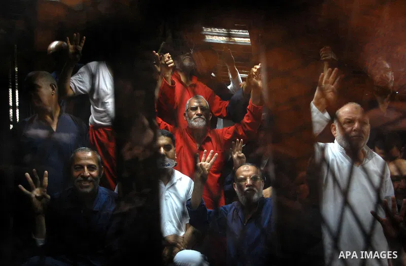 Muslim Brotherhood's Supreme Guide Mohamed Badie sits behind bars with other Muslim Brotherhood members at a court in the outskirts of Cairo, Egypt May 16, 2015. An Egyptian court on Saturday sought the death penalty for...