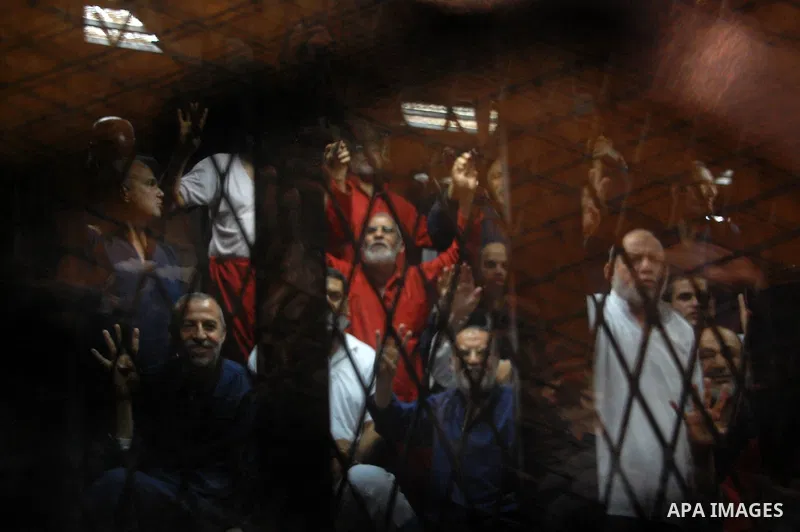 Muslim Brotherhood's Supreme Guide Mohamed Badie sits behind bars with other Muslim Brotherhood members at a court in the outskirts of Cairo, Egypt May 16, 2015. An Egyptian court on Saturday sought the death penalty for...