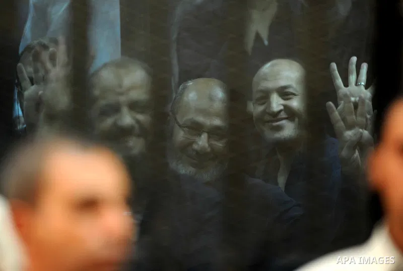 Egyptian Muslim Brotherhood top figure, Mohamed el-Beltagy flashes the four finger symbol known as "Rabaa" from behind the defendant's cage as the judge reads out the verdict sentencing him and more than 100 other defend...