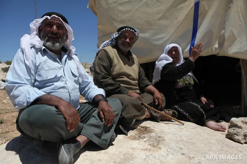 Palestinians sit outside their tent during a protest against an Israeli decision to demolish the village of Susia outside the West Bank village of Yatta in southern of Hebron, on May 16, 2015. Palestinians are not allowe...