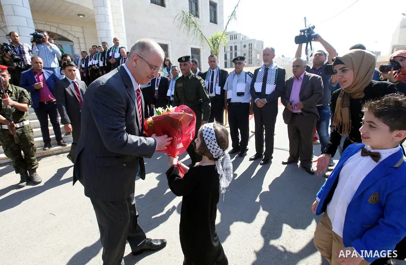 Palestinian girl offers roses to Palestinian Prime Minister Rami Hamdallah before his meeting with security managers in the West Bank city of Tulkarem on May 16, 2015. Photo by Prime Minister Office