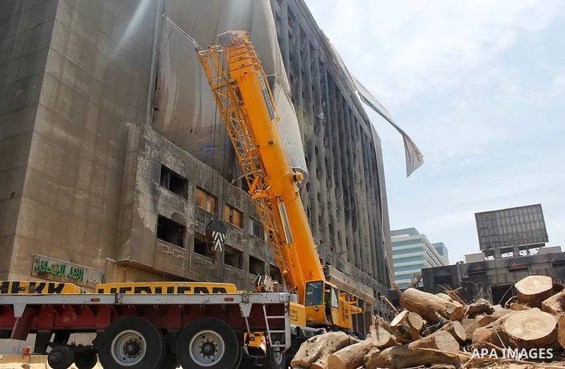 Egyptian workers use a crane to pull down National Democratic Party building, in Cairo on May 17, 2015. Last month, the Egyptian cabinet made a decision to pull down the headquarters of the currently-dismantled National...