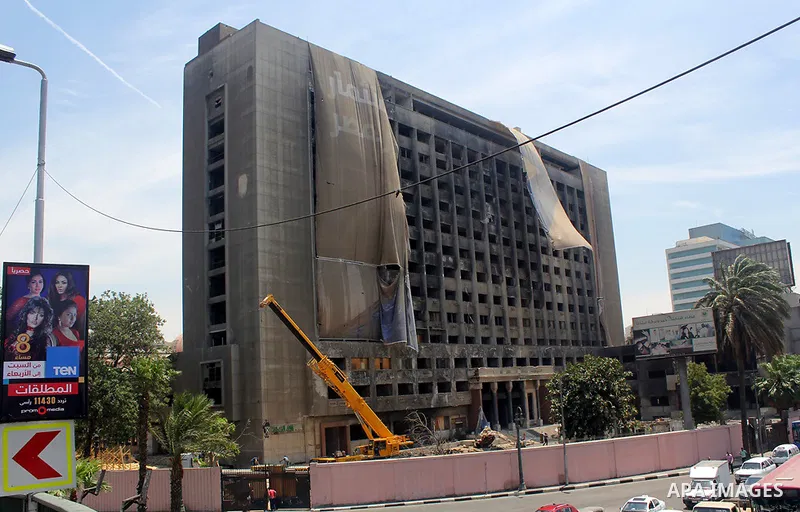 Egyptian workers use a crane to pull down National Democratic Party building, in Cairo on May 17, 2015. Last month, the Egyptian cabinet made a decision to pull down the headquarters of the currently-dismantled National...