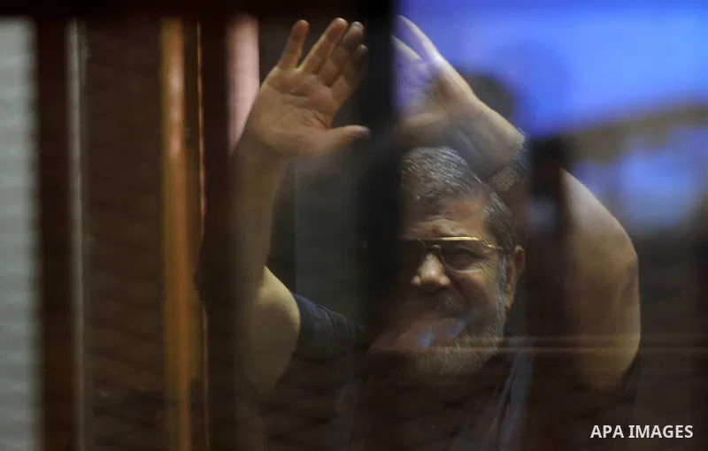 Egypt's deposed Islamist president Mohamed Morsi, is seen behind bars during his trial in a case of the "communicating with Qatar" at the court, in Cairo, on May 19, 2015. Photo by Stringer