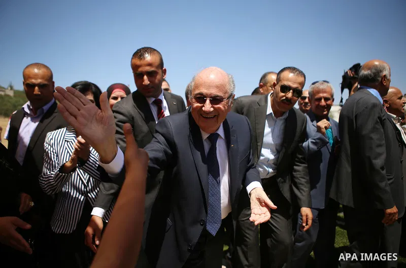 FIFA president Joseph Blatter (R) shakes hands with Palestinian children during his visit to the sports club in the village of Dura al-Qaraa, near the West Bank city of Ramallah, on May 20, 2015. Blatter hopes to head of...