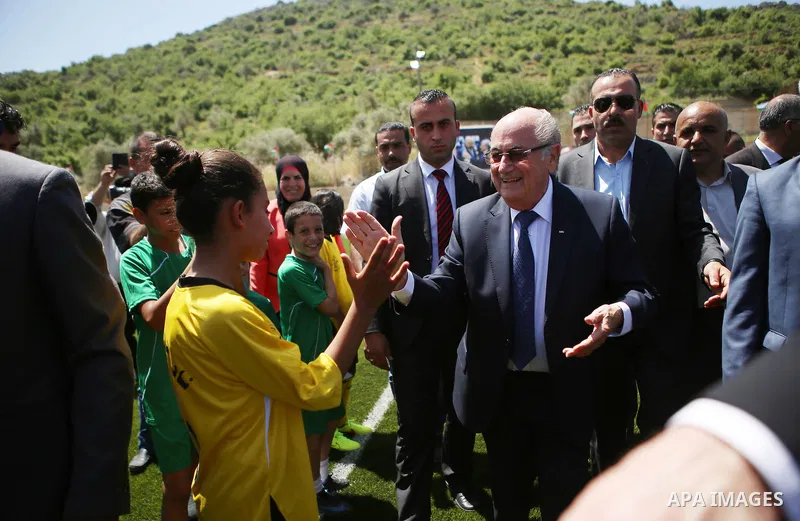 FIFA president Joseph Blatter (R) shakes hands with Palestinian children during his visit to the sports club in the village of Dura al-Qaraa, near the West Bank city of Ramallah, on May 20, 2015. Blatter hopes to head of...