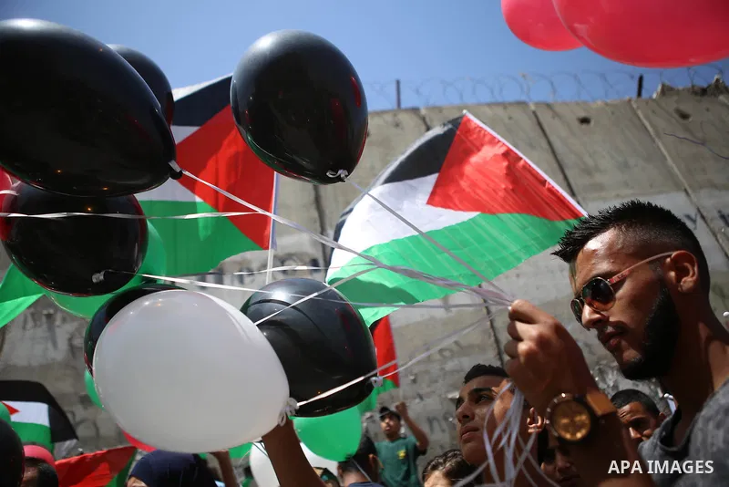 Palestinians hold flags and balloons during a protest against the Israeli separation wall in the West Bank town of al-Ram, near Jerusalem, on May 21, 2015. Photo by Shadi Hatem