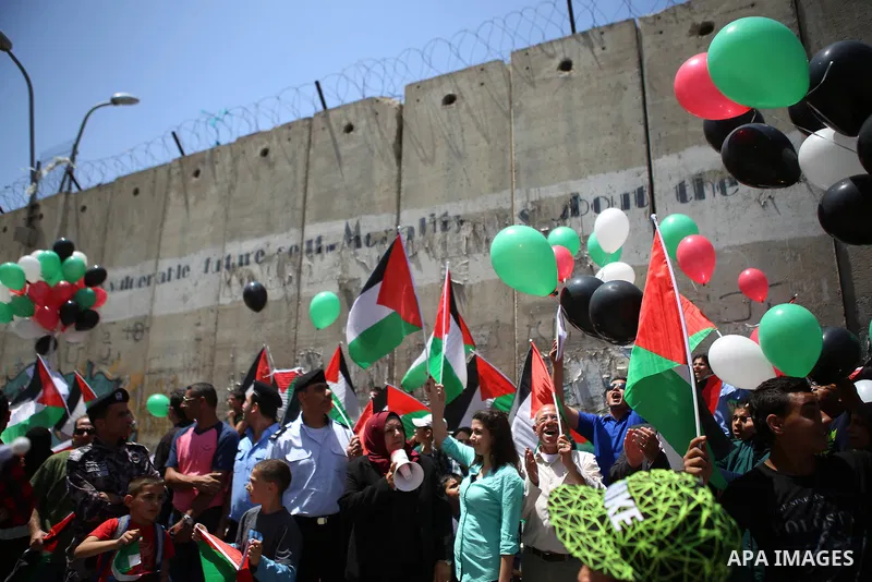 Palestinians hold flags and release balloons towards Jerusalem during a protest against the Israeli separation wall in the West Bank town of al-Ram, near Jerusalem, on May 21, 2015. Photo by Shadi Hatem