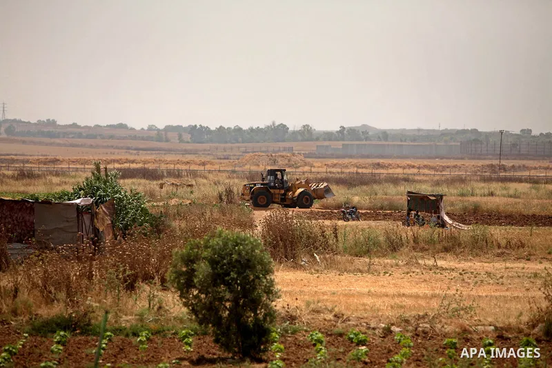 Palestinian workers use a bulldozer to build a street near the border with Israel, in Gaza City, on May 23, 2015. Photo by Ashraf Amra
