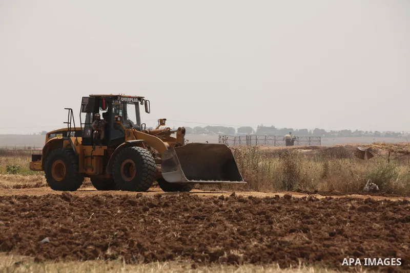 Palestinian workers use a bulldozer to build a street near the border with Israel, in Gaza City, on May 23, 2015. Photo by Ashraf Amra