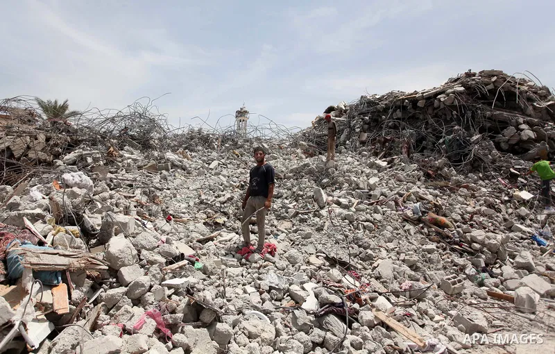 Palestinian men work amid the rubble of houses which were destroyed during the 50-day war between Israel and Hamas militants in the summer of 2014, in the Eastern Gaza City Shujaiya neighbourhood, on May 23, 2015. Photo...