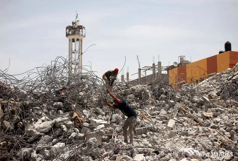 Palestinian men work amid the rubble of houses which were destroyed during the 50-day war between Israel and Hamas militants in the summer of 2014, in the Eastern Gaza City Shujaiya neighbourhood, on May 23, 2015. Photo...