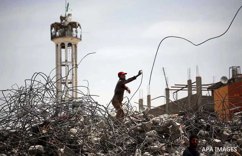 Palestinian men work amid the rubble of houses which were destroyed during the 50-day war between Israel and Hamas militants in the summer of 2014, in the Eastern Gaza City Shujaiya neighbourhood, on May 23, 2015. Photo...