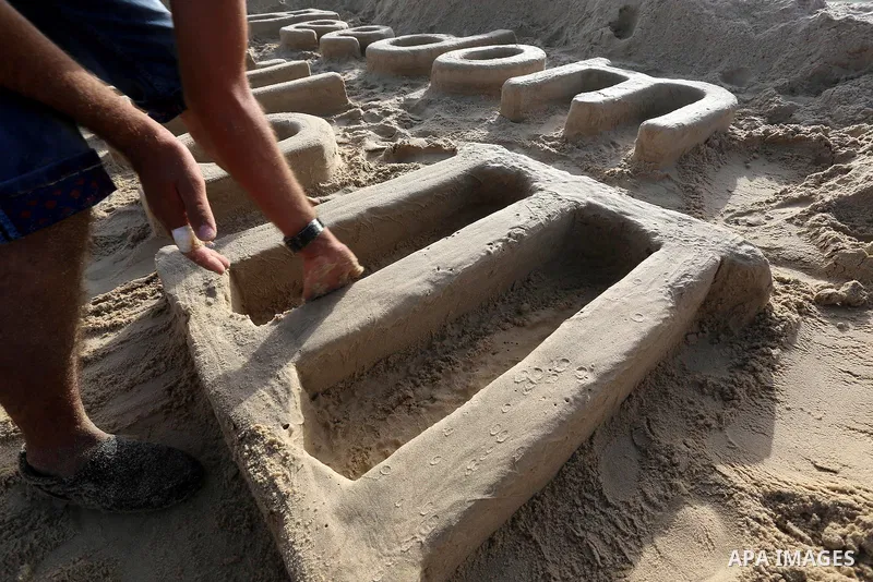 A Palestinian man creates a sand sculpture reads ''Freedom Flotilla III'' at the beach of Gaza city, 24 May, 2015. The first ship taking part in Freedom Flotilla III last week set sail from Gothenburg, Sweden, for a voya...