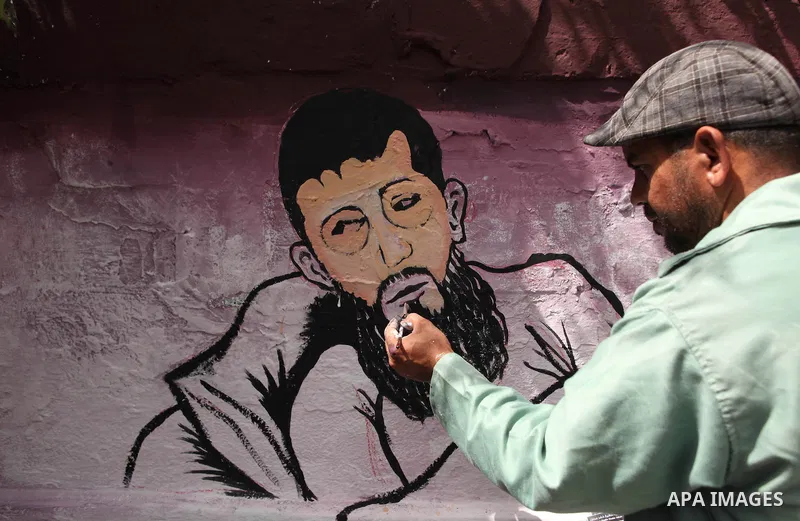 A Palestinian artist paints a mural depicting of Khader Adnan, a senior member of Islamic Jihad jailed in Israel, during a protest calling for the release of Adnan, in front of Red cross office, in Gaza city, on May 25,...