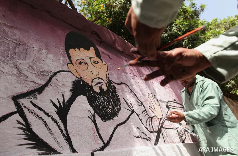 A Palestinian artist paints a mural depicting of Khader Adnan, a senior member of Islamic Jihad jailed in Israel, during a protest calling for the release of Adnan, in front of Red cross office, in Gaza city, on May 25,...