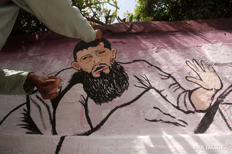 A Palestinian artist paints a mural depicting of Khader Adnan, a senior member of Islamic Jihad jailed in Israel, during a protest calling for the release of Adnan, in front of Red cross office, in Gaza city, on May 25,...