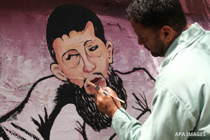 A Palestinian artist paints a mural depicting of Khader Adnan, a senior member of Islamic Jihad jailed in Israel, during a protest calling for the release of Adnan, in front of Red cross office, in Gaza city, on May 25,...