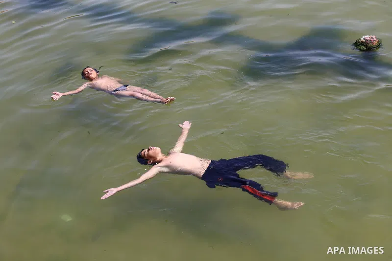 Palestinian youths swim into the Mediterranean Sea as they enjoy a warm day at the seaport in Gaza City on May 25, 2015. Photo by Mohammed Asad