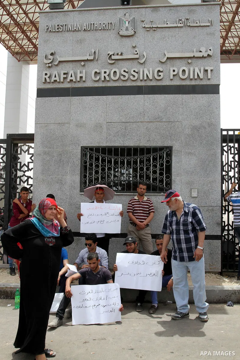Palestinian youths hold banners in a protest demanding open Rafah crossing, outside the Rafah border crossing between Egypt and southern Gaza Strip May 26, 2015. Egyptian authorities opened the Rafah crossing on Tuesday,...