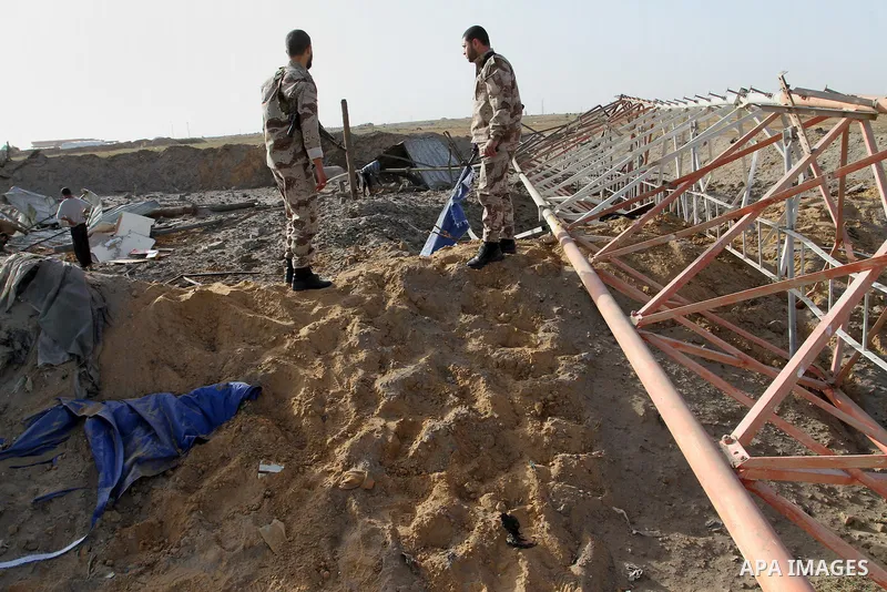 Palestinian security men look at a crater on the ground following an Israeli airstrike in the southern Gaza Strip near the town, of Rafah on May 27,2015. The Israeli air force carried out four strikes on militant targets...