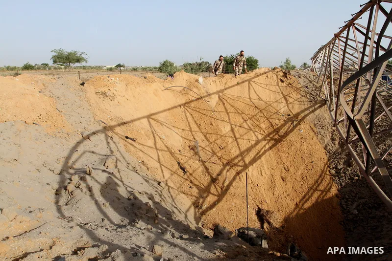 Palestinian security men look at a crater on the ground following an Israeli airstrike in the southern Gaza Strip near the town, of Rafah on May 27,2015. The Israeli air force carried out four strikes on militant targets...