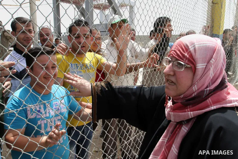 A Palestinian woman waves to her relatives standing behind a fence upon her return to Gaza through Rafah border crossing between Egypt and southern Gaza Strip May 27, 2015. Egyptian authorities opened the Rafah crossing...