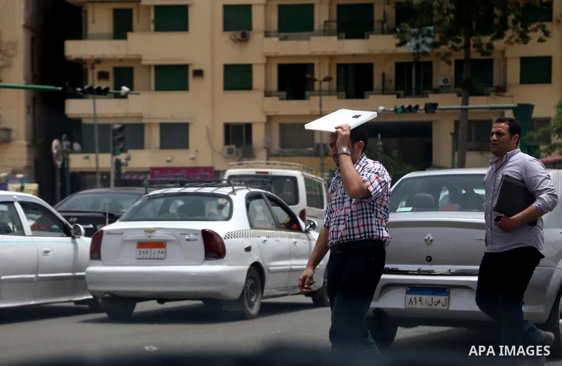Egyptians walk in a street in downtown Cairo on May 27, 2015. Hot weather with sandstorm hit Egypt on Wednesday, and the temperature reached 44 degree Celsius (111 degree Fahrenheit) at noon in some regions of the countr...