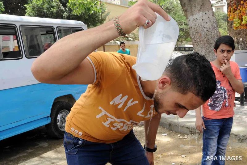 An Egyptian man washes himself with cold water in a street in downtown Cairo on May 27, 2015. Hot weather with sandstorm hit Egypt on Wednesday, and the temperature reached 44 degree Celsius (111 degree Fahrenheit) at no...