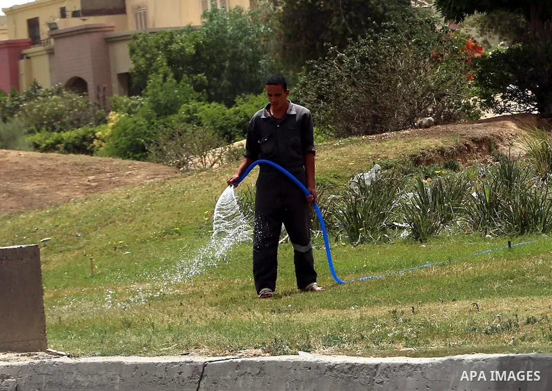 An Egyptian man sprays water at a garden in downtown Cairo on May 27, 2015. Hot weather with sandstorm hit Egypt on Wednesday, and the temperature reached 44 degree Celsius (111 degree Fahrenheit) at noon in some regions...