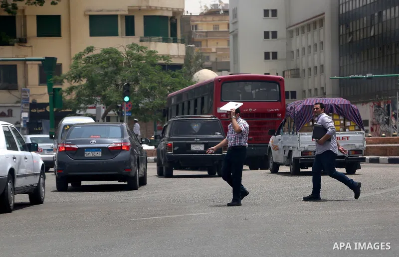 Egyptians walk in a street in downtown Cairo on May 27, 2015. Hot weather with sandstorm hit Egypt on Wednesday, and the temperature reached 44 degree Celsius (111 degree Fahrenheit) at noon in some regions of the countr...