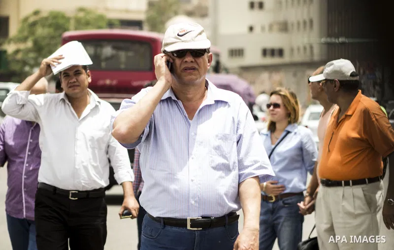 Egyptians walk in a street in downtown Cairo on May 27, 2015. Hot weather with sandstorm hit Egypt on Wednesday, and the temperature reached 44 degree Celsius (111 degree Fahrenheit) at noon in some regions of the countr...