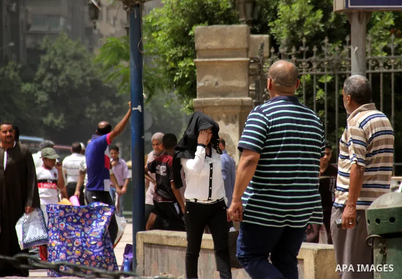 Egyptians walk in a street in downtown Cairo on May 27, 2015. Hot weather with sandstorm hit Egypt on Wednesday, and the temperature reached 44 degree Celsius (111 degree Fahrenheit) at noon in some regions of the countr...