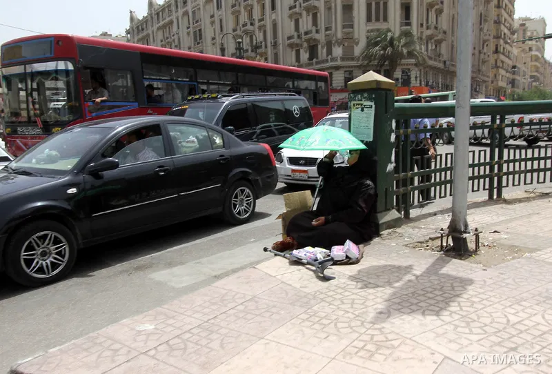 Egyptians walk in a street in downtown Cairo on May 27, 2015. Hot weather with sandstorm hit Egypt on Wednesday, and the temperature reached 44 degree Celsius (111 degree Fahrenheit) at noon in some regions of the countr...