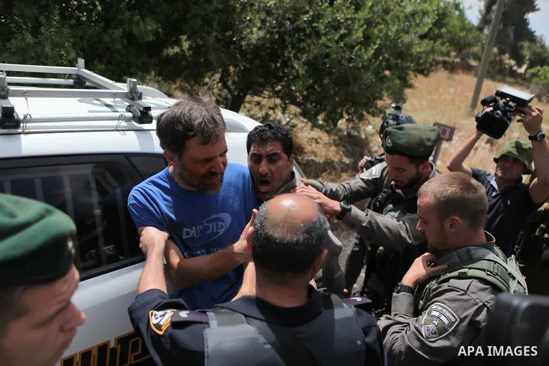 Israeli security try to detain a Palestinian and Israeli protesters during a demonstration outside al-Barak building, near al-Aroub Palestinian refugee camp, just north the West Bank town of Hebron on May 30, 2015, again...