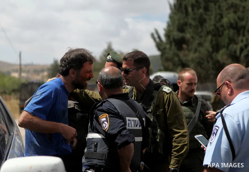 Israeli security try to detain a Palestinian and Israeli protesters during a demonstration outside al-Barak building, near al-Aroub Palestinian refugee camp, just north the West Bank town of Hebron on May 30, 2015, again...