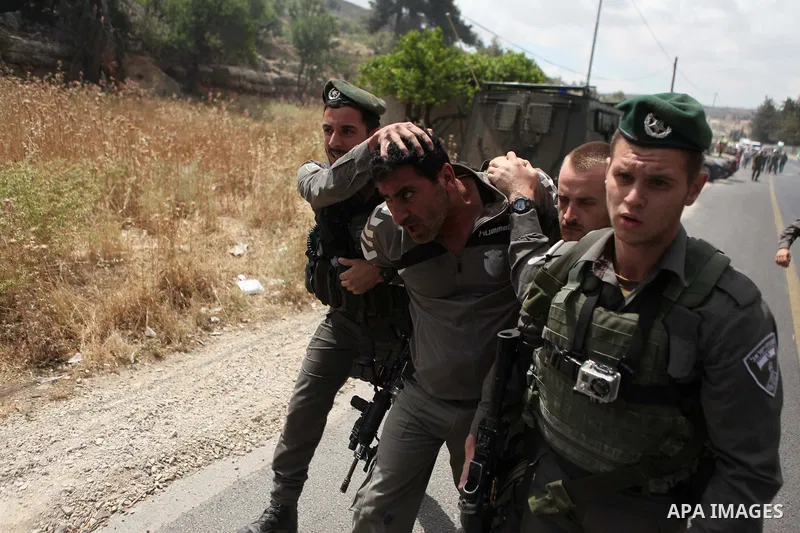 Israeli security try to detain a Palestinian protester during a demonstration outside al-Barak building, near al-Aroub Palestinian refugee camp, just north the West Bank town of Hebron on May 30, 2015, against the sale o...