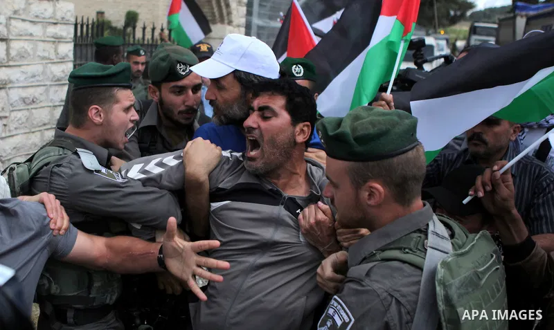 Israeli security try to detain a Palestinian protester during a demonstration outside al-Barak building, near al-Aroub Palestinian refugee camp, just north the West Bank town of Hebron on May 30, 2015, against the sale o...