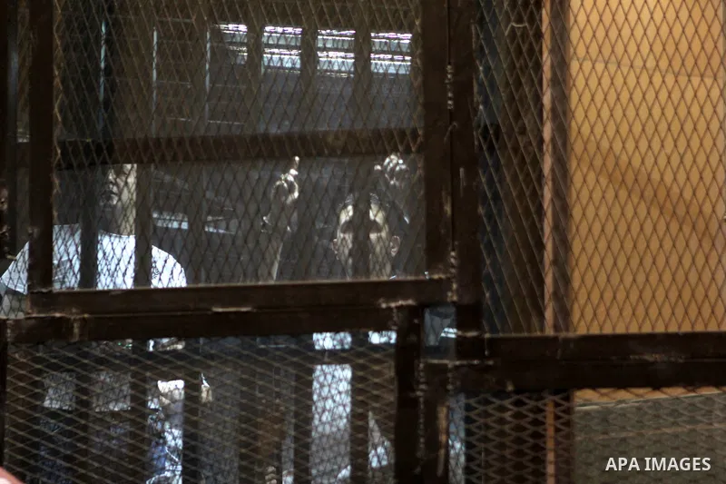 Egyptian defendants sit behind bars during their trial over a 2012 stadium riot in the canal city of Port Said that left 74 people dead on May 30, 2015 at the police academy in Cairo. The Egyptian court postponed its ver...