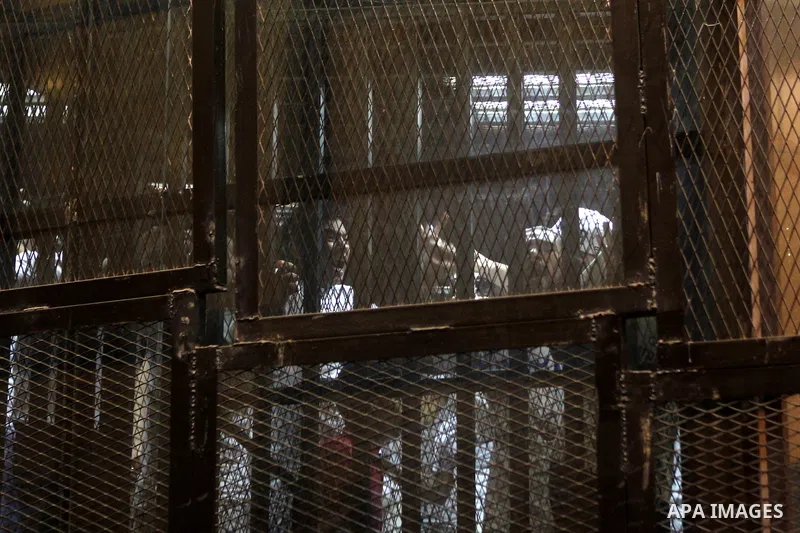 Egyptian defendants sit behind bars during their trial over a 2012 stadium riot in the canal city of Port Said that left 74 people dead on May 30, 2015 at the police academy in Cairo. The Egyptian court postponed its ver...