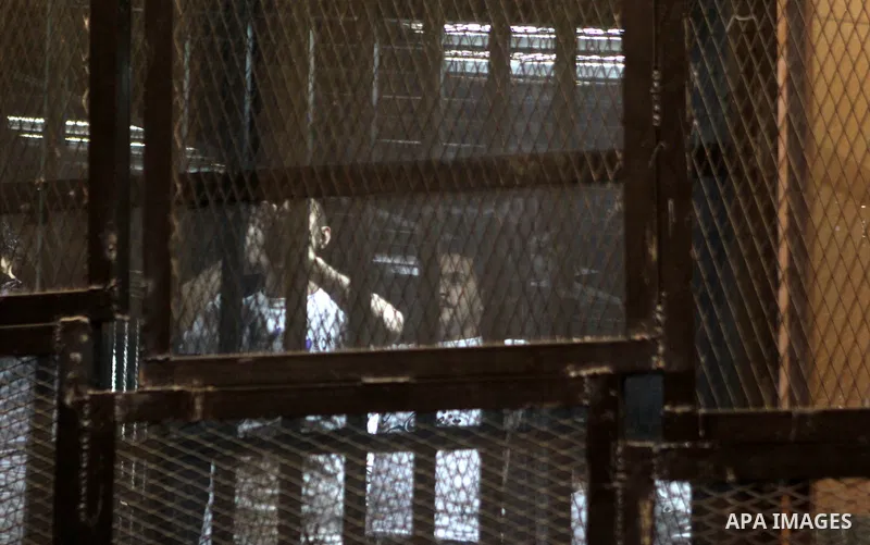 Egyptian defendants sit behind bars during their trial over a 2012 stadium riot in the canal city of Port Said that left 74 people dead on May 30, 2015 at the police academy in Cairo. The Egyptian court postponed its ver...