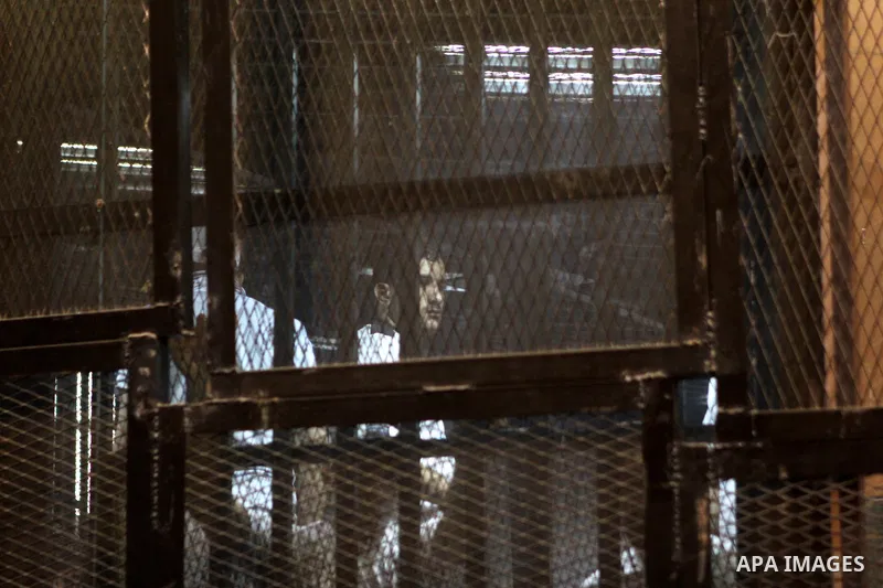 Egyptian defendants sit behind bars during their trial over a 2012 stadium riot in the canal city of Port Said that left 74 people dead on May 30, 2015 at the police academy in Cairo. The Egyptian court postponed its ver...