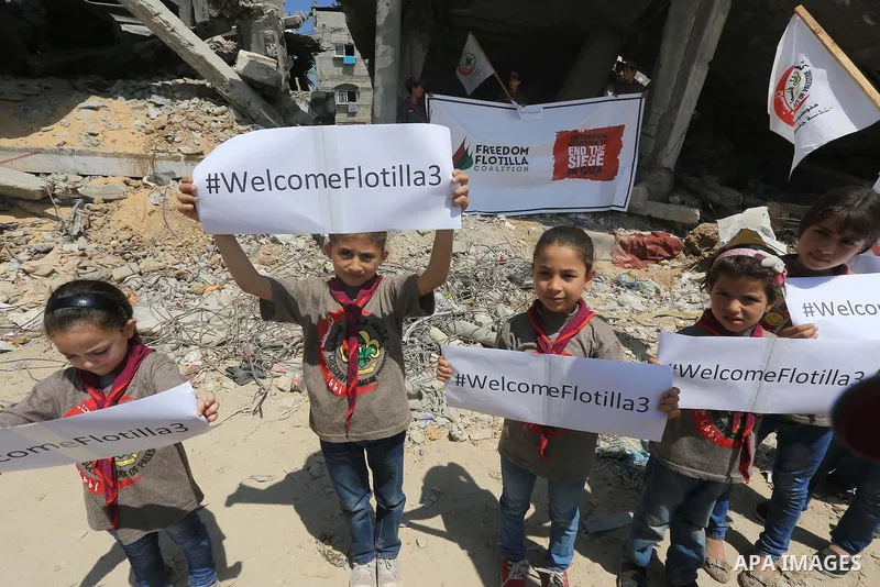 Palestinian children hold banners during a rally in front of the houses, which were damaged during the recent Israeli war, in Shejaiya neighborhood in Gaza city, on May 31, 2015. The first ship taking part in Freedom Flo...