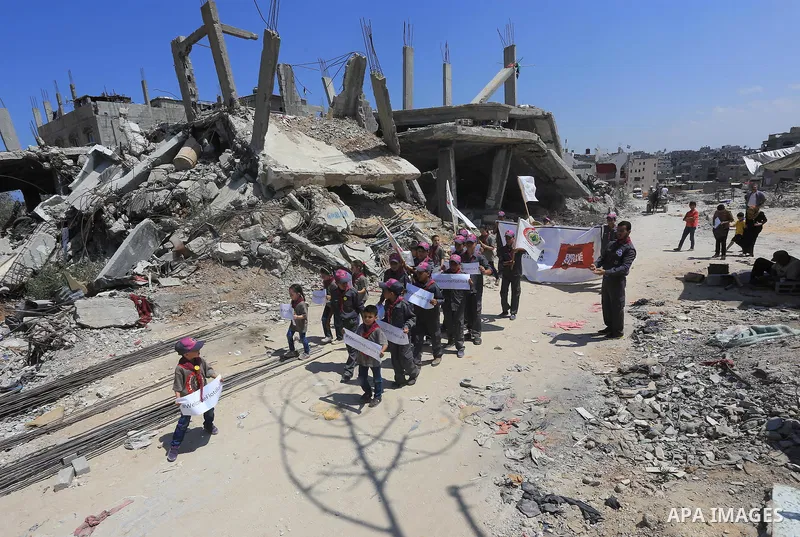 Palestinian children hold banners during a rally in front of the houses, which were damaged during the recent Israeli war, in Shejaiya neighborhood in Gaza city, on May 31, 2015. The first ship taking part in Freedom Flo...