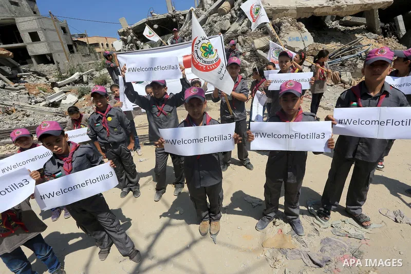 Palestinian children hold banners during a rally in front of the houses, which were damaged during the recent Israeli war, in Shejaiya neighborhood in Gaza city, on May 31, 2015. The first ship taking part in Freedom Flo...