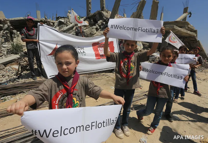 Palestinian children hold banners during a rally in front of the houses, which were damaged during the recent Israeli war, in Shejaiya neighborhood in Gaza city, on May 31, 2015. The first ship taking part in Freedom Flo...