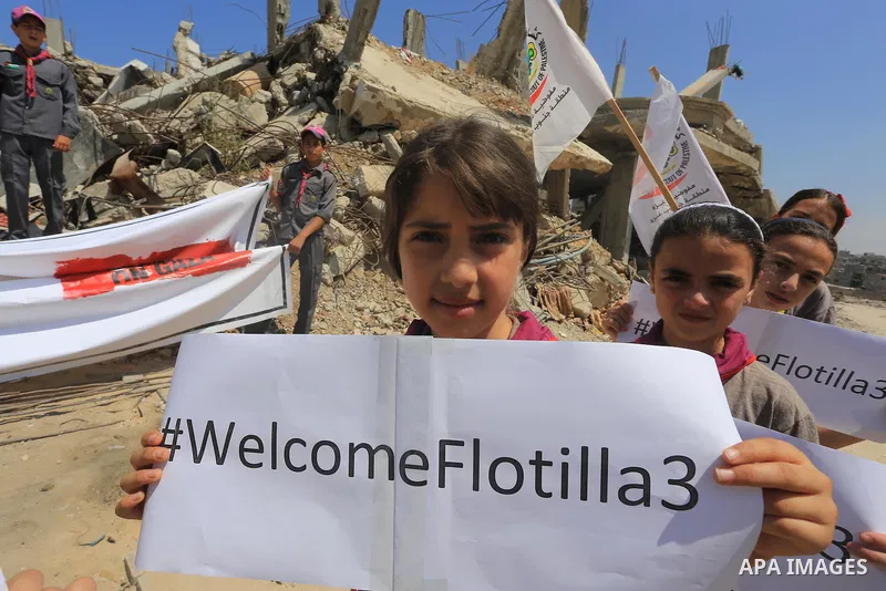 Palestinian children hold banners during a rally in front of the houses, which were damaged during the recent Israeli war, in Shejaiya neighborhood in Gaza city, on May 31, 2015. The first ship taking part in Freedom Flo...