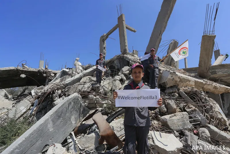 Palestinian children hold banners during a rally in front of the houses, which were damaged during the recent Israeli war, in Shejaiya neighborhood in Gaza city, on May 31, 2015. The first ship taking part in Freedom Flo...