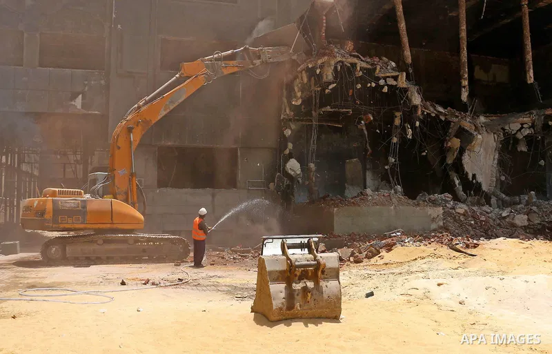 An Egyptian worker sprays water during the demolition of the headquarters of the once-dominant party of ex-president Hosni Mubarak that was torched during the 2011 uprising that toppled him, on May 31, 2015 in the capita...