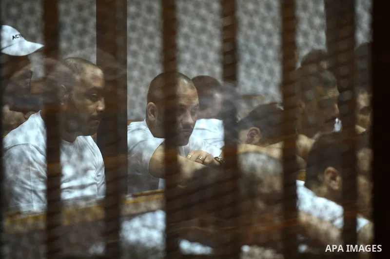 Egyptian defendants sit behind bars during their trial over a 2012 stadium riot in the canal city of Port Said that left 74 people dead on May 31, 2015 at the police academy in Cairo. The Egyptian court postponed its ver...